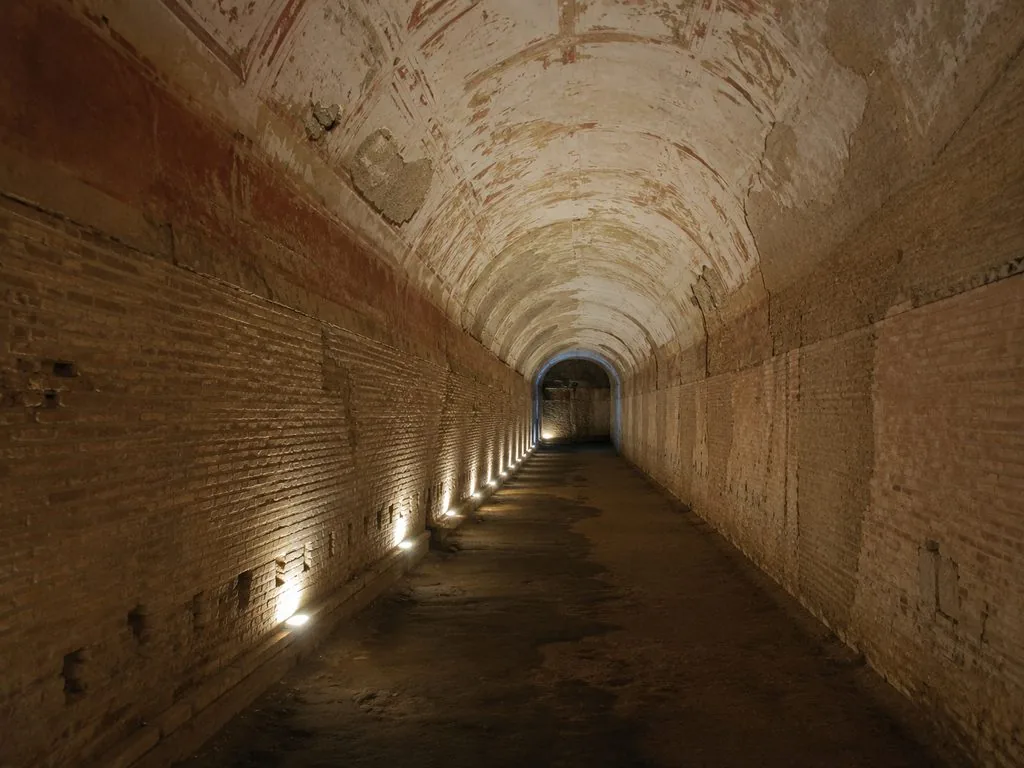 A barrel-vaulted corridor in bare brick and concrete inside the Domus Aurea